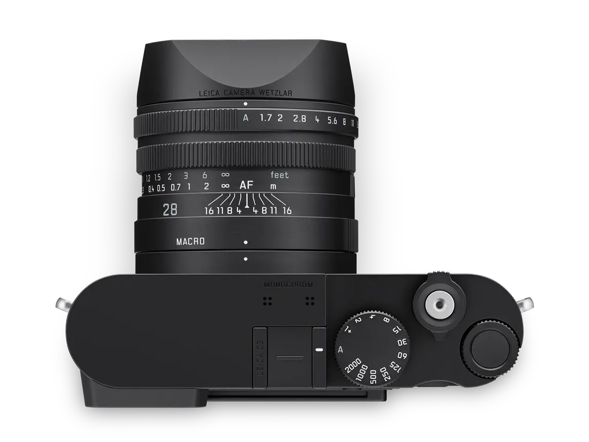 Leica Q3 Monochrom in der Draufsicht mit Summilux 28 mm f1.7 ASPH. und aufgesetzter Gegenlichtblende